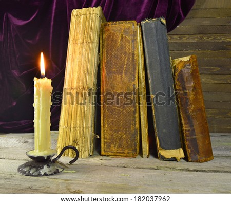 Old library books with burning candle on the table