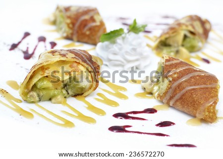 Delicious crepes with fruit and cream, decorated with sauce patterns, restaurant menu dish on white