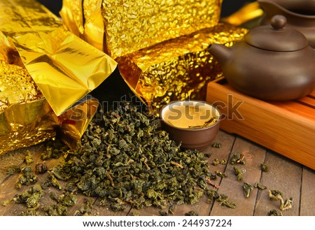 Still life with raw tea leaves in golden packages and tea set for asian tea ceremony, chinese culture concept image, alternative medicine still life