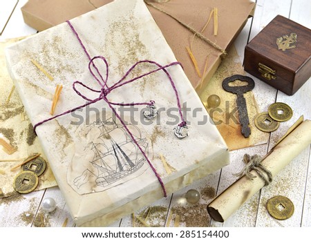 Marine still life with decorated wrapped gifts and retro objects: key, paper scroll, ancient coins, old paper