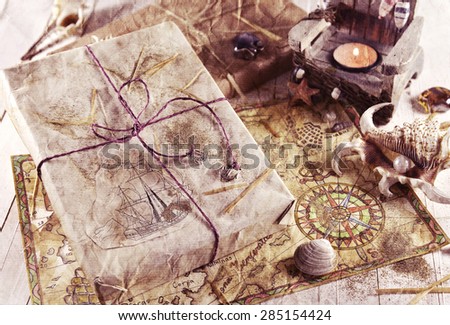 Retro still life with wrapped gift, shells and hand drawn pirate map, image filtered and textured