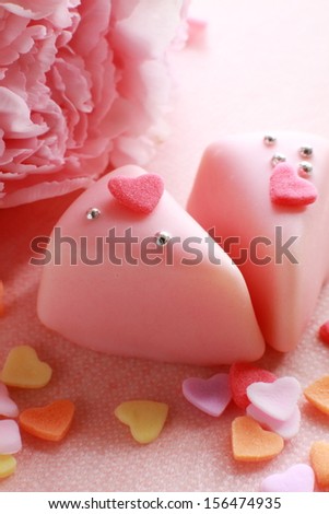 Two Valentine\'s-themed cakes sit next to a carnation and candy hearts