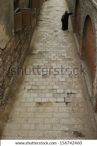 Woman wearing religious dress standing in lane leaning on wall