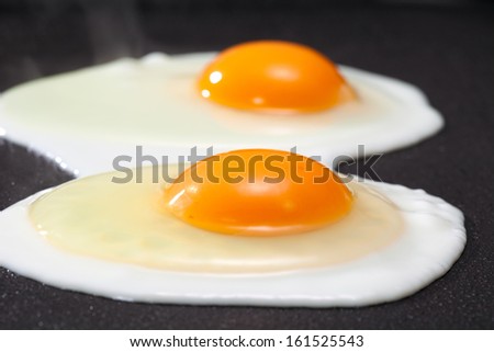 Two eggs on a grill sunny side up.