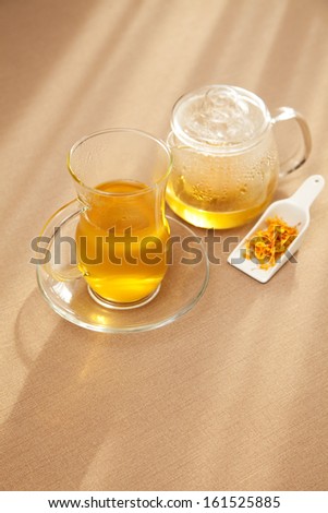 A glass of yellow liquid on a dish.