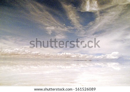 Pure white shoreline with white thin clouds scattering the blue sky.