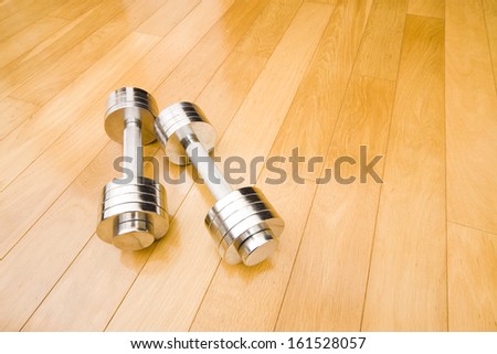 A set of stainless steel free weights shining on an all wood floor.