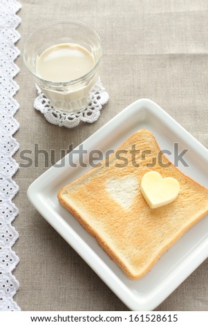 Heart shaped butter sits atop a piece of toast.