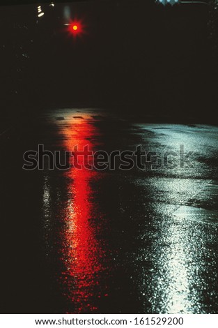 A wet street reflecting a traffic light.