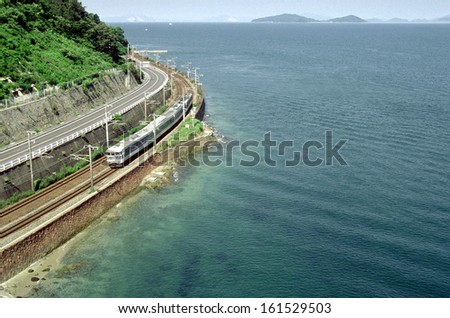 A train travels on a track next to a clear blue ocean.