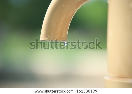 A single droplet of water is leaking from a pipe.