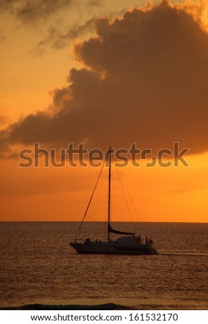 Sailing in an amber sunset on the calm ocean.