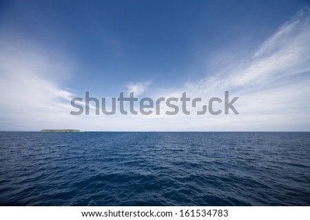 A blue ocean meeting a blue sky along a horizon.