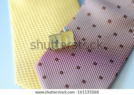 Two pieces of material with a small item on top. One piece of material is yellow and the other is pink with regular markings.