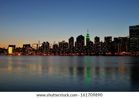 A body of water in front of a large city in the evening.