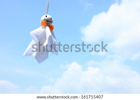 A hanging toy with an orange neck tie with a cloudy sky as background.