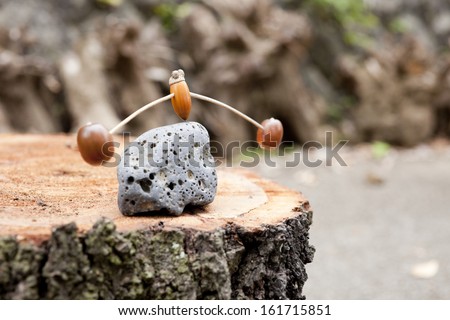 A toy balances on a rock on a tree stump.