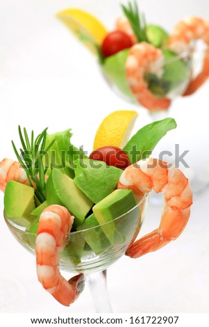 Two cups of shrimp cocktail with avocado, tomato, lemon, and lettuce.