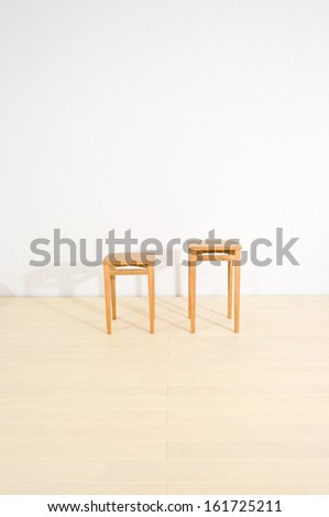 A pair of wooden end tables casting shadows on a white wall.