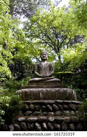 A brown stone statue sitting in the middle of a lush green forest.
