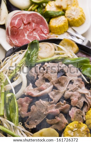 A steaming stir-fry pan filled with meat and vegetables.