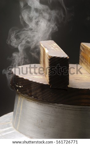 Steam coming from an oven covered by a wooden lid.