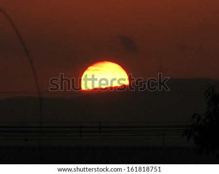 A large yellow sun setting into the hills.
