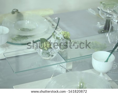 A glass table with an assortment of dishes and two glass birds.