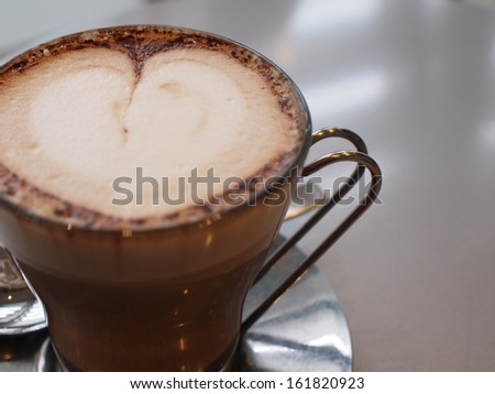A brown coffee mug filled with liquid in the shape of a heart.