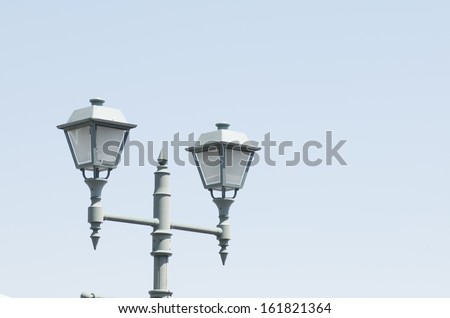 A clear blue sky with a set of streets lamps on a gray stake.