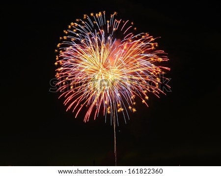 Looking up at bright orange and blue fireworks.
