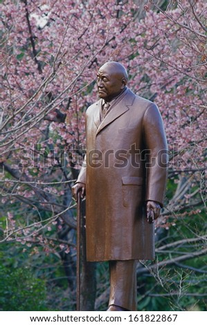 A bronze statue of a man in front of a tree.