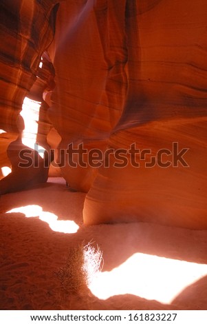 Red rock walls with a sand bottom and the sun shining in.