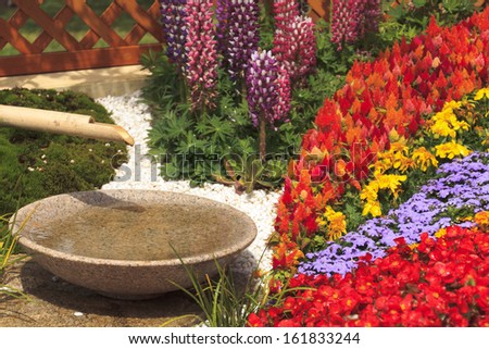 Traditional water drinking fountain with flowers in a garden