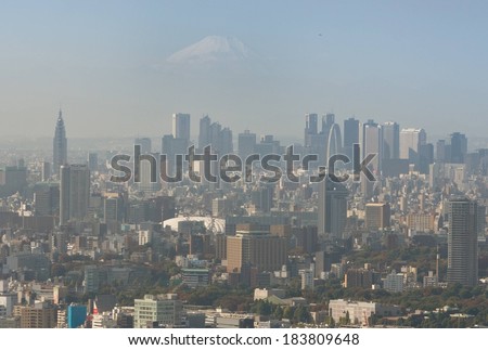 An extreme long shot overlooking a large, hazy city under Mt Fuji.
