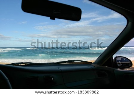 A view of the ocean and horizon through the windshield of a vehicle.