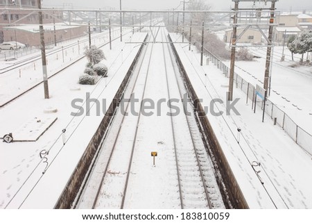A railroad track covered in a light layer of snow.