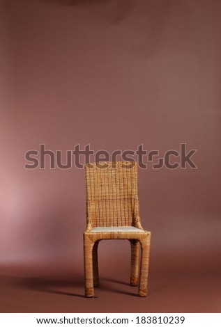A wicker chair standing alone in a room.