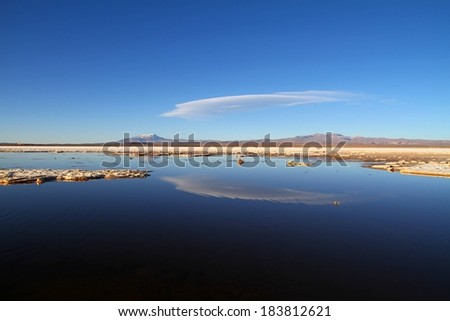 A blue sky and land formations in water.