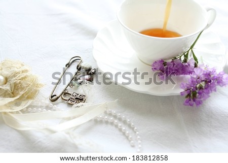 A pile of jewelry next to a cup of tea.