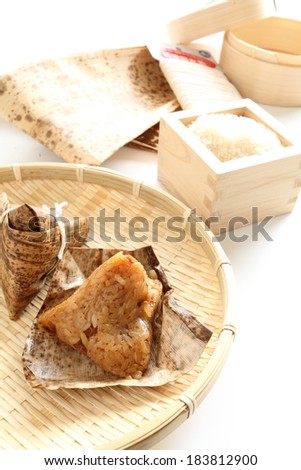 A mixture of food stuffs served on a wicker plate and wooden rice container.