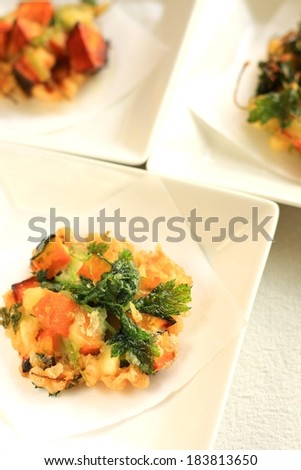 Three square dishes containing a food mixture with greens on top.