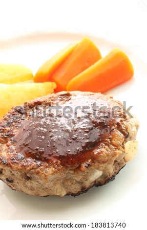 A meat patty with vegetables on the side.