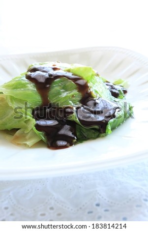 Lettuce-wrapped food on a white plate with a brown sauce drizzled over it.