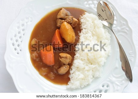 A fancy white dinner plate with rice and gravy mixture with meat and vegetables.
