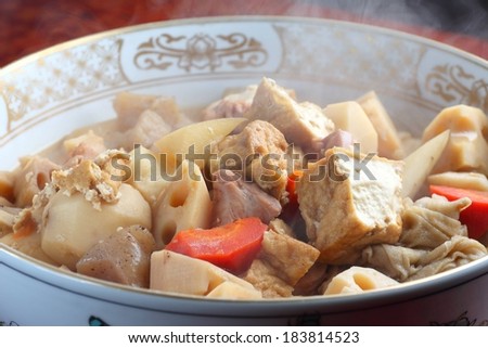 A bowl full of meat and potatoes in a broth.