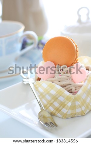 A checkered box of sweet treats and desserts with a teacup and saucer in the background.