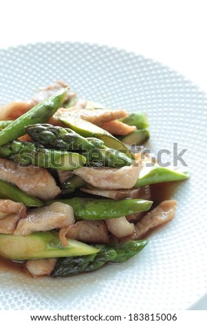 A white dish on a table with chicken and asparagus on it.