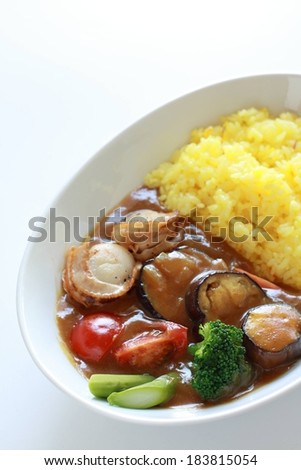 A white dish of rice, veggies and some brown sauce.