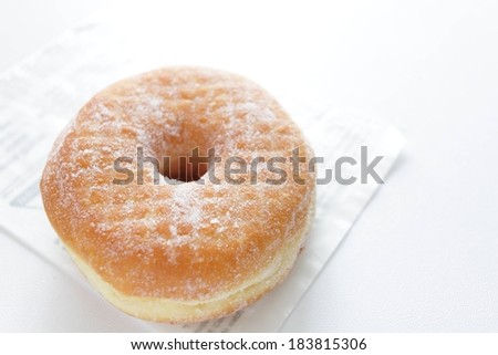 A sugar covered doughnut sitting on a piece of paper.